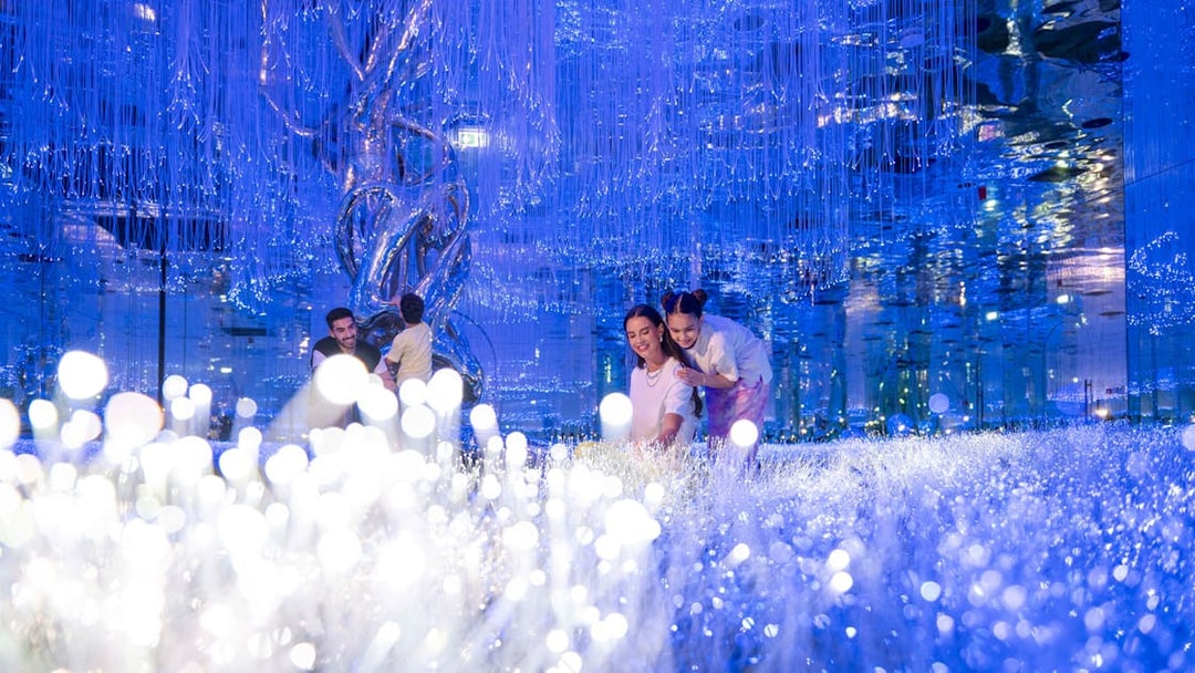 Visitors exploring the illuminated installations at AYA Universe.