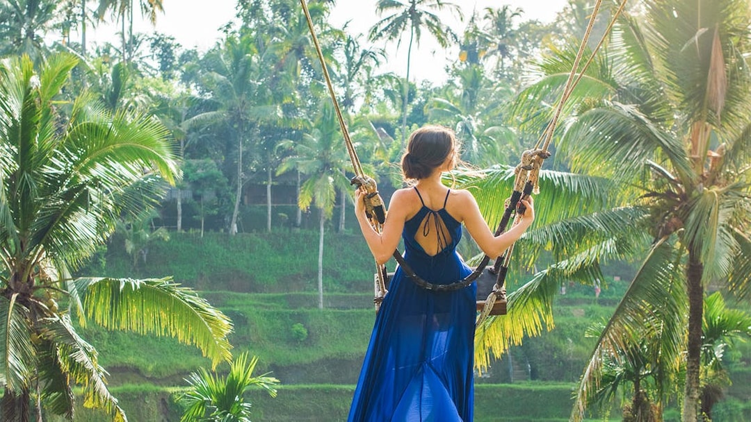 Person on swing overlooking Bali rice terraces during private tour.