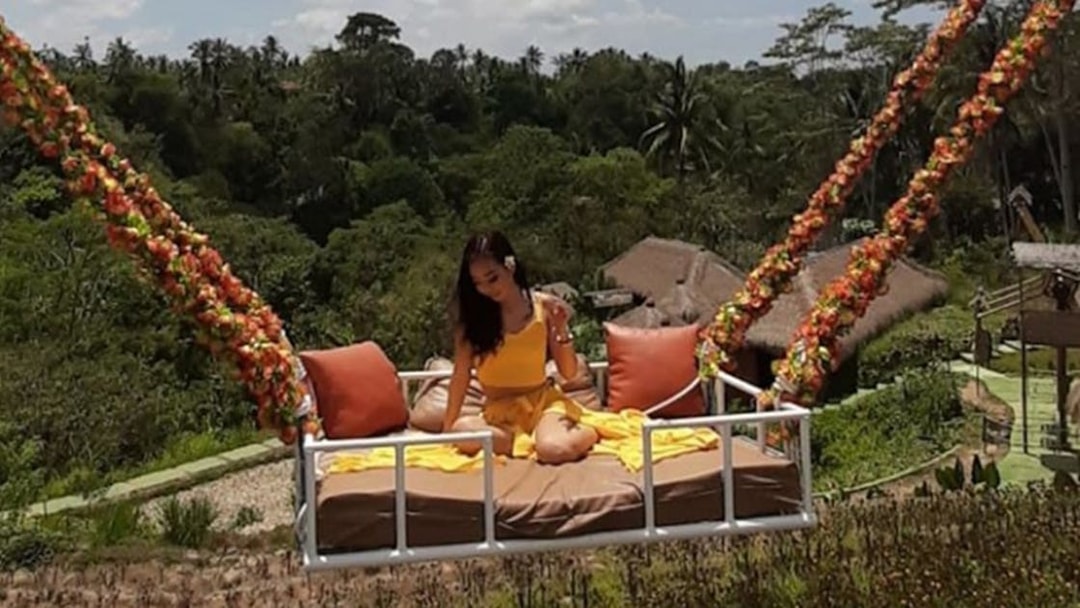 Woman on a swing overlooking lush greenery in Bali during a private tour.