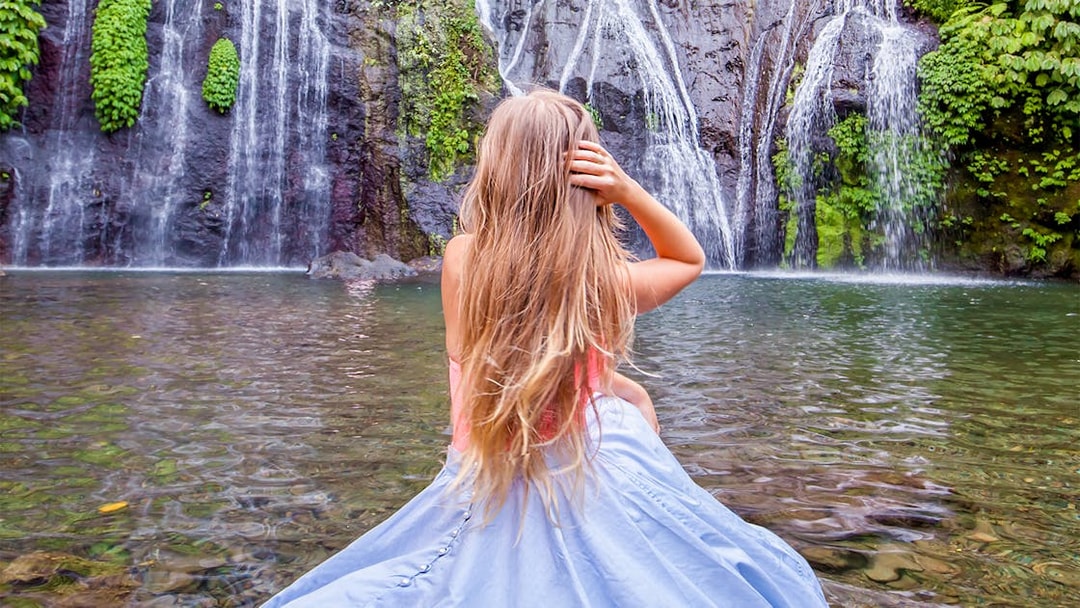 Person sitting by a waterfall in Bali, Indonesia, during a private tour.