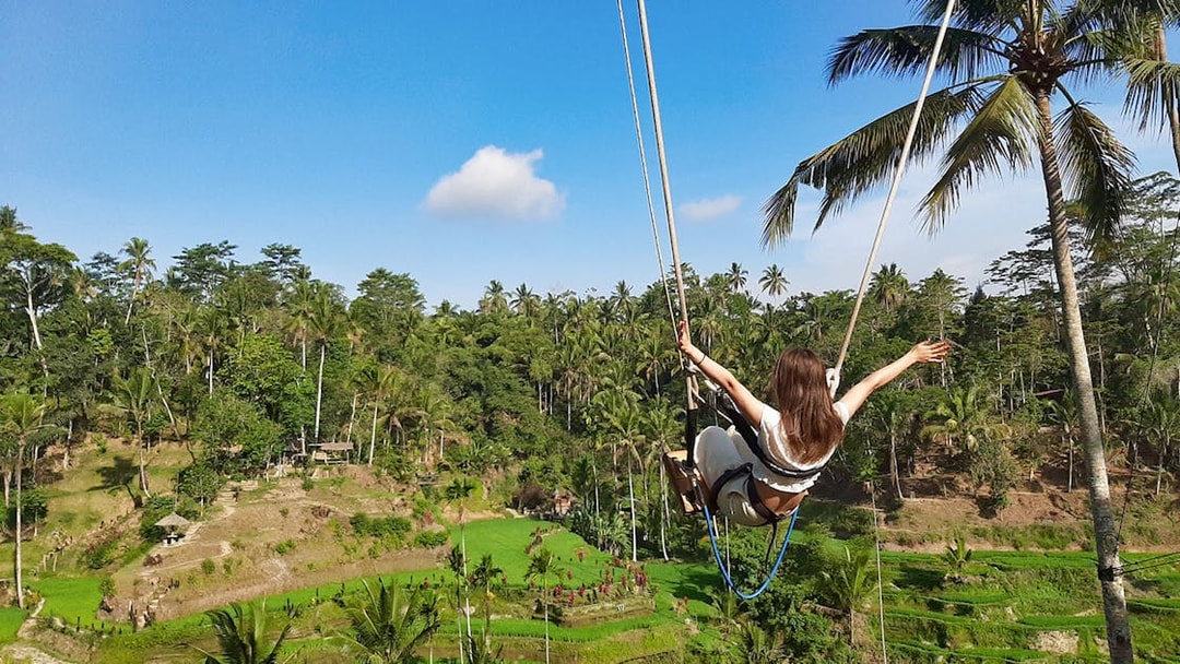 Person swinging over rice terraces in Bali during a private tour.