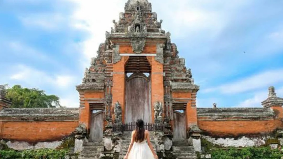 Balinese temple gate with visitor in traditional dress, Bali Fullday Private Customized Tour.