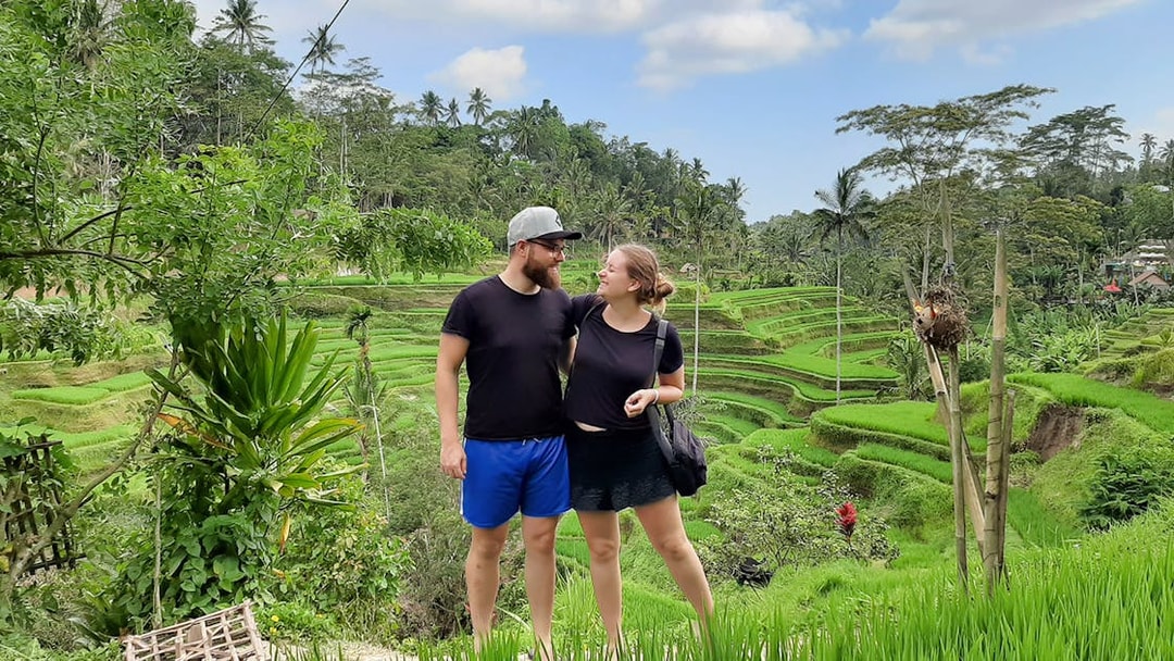 Couple standing in front of Tegallalang Rice Terraces, Bali, during a scenic Instagram tour.