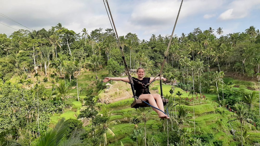 Person on a swing over lush rice terraces in Bali, Indonesia.