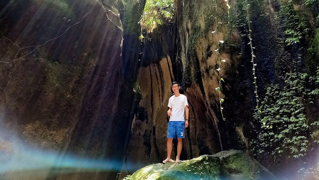 Man standing in a sunlit cave with lush greenery, Bali Instagram Private Tour.