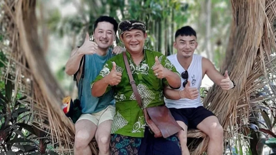 Tourists posing with a local guide in a scenic Bali jungle setting.