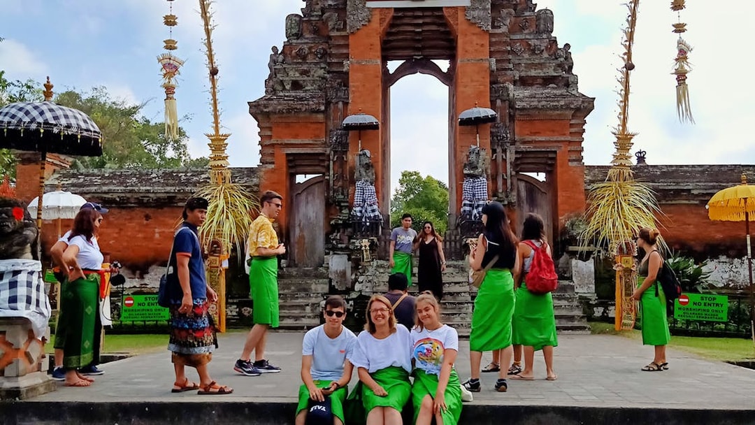 Balinese temple entrance with tourists in traditional sarongs, Bali Private Bedugul, Tanah Lot Sunset Tour.
