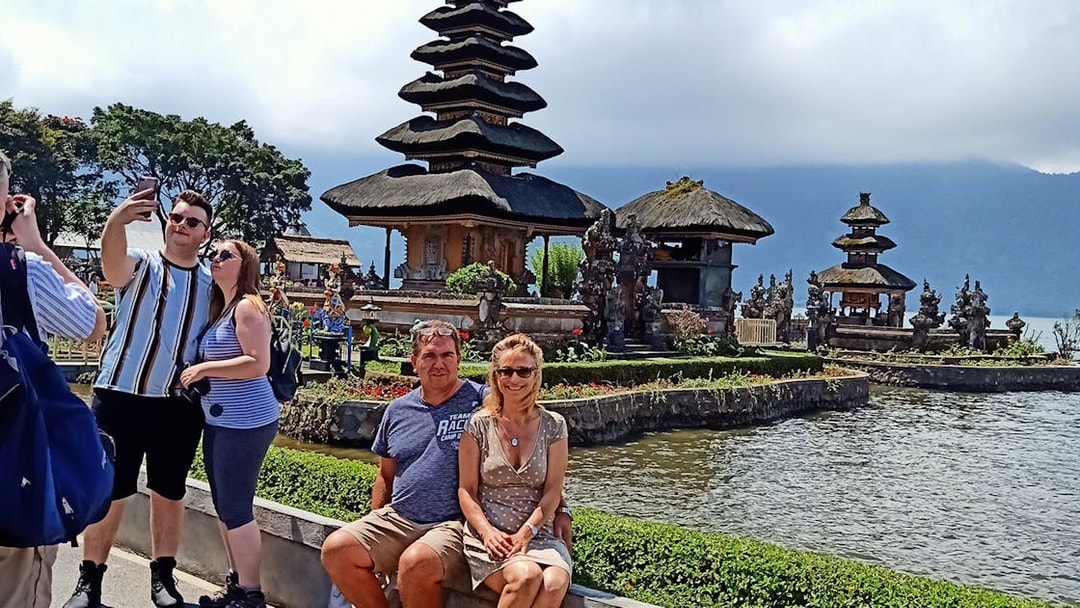 Bali Bedugul temple with tourists taking photos by the water.