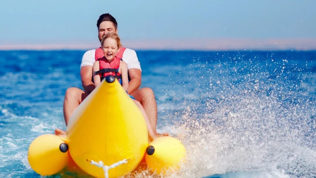 Family riding a banana boat on the sea in Dubai.
