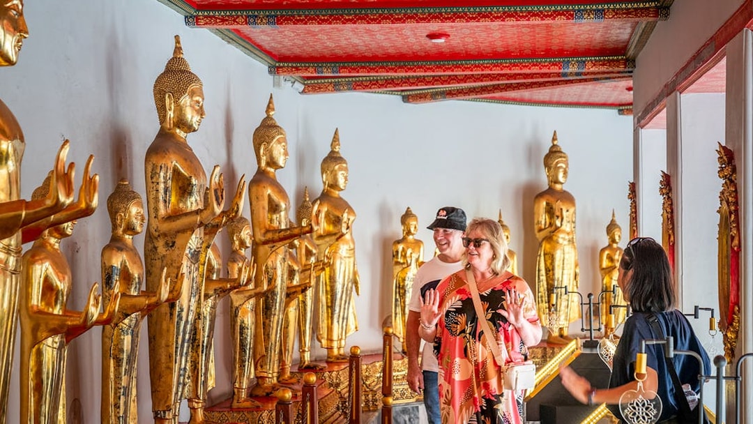 Tourists exploring golden Buddha statues at Wat Pho, Bangkok.