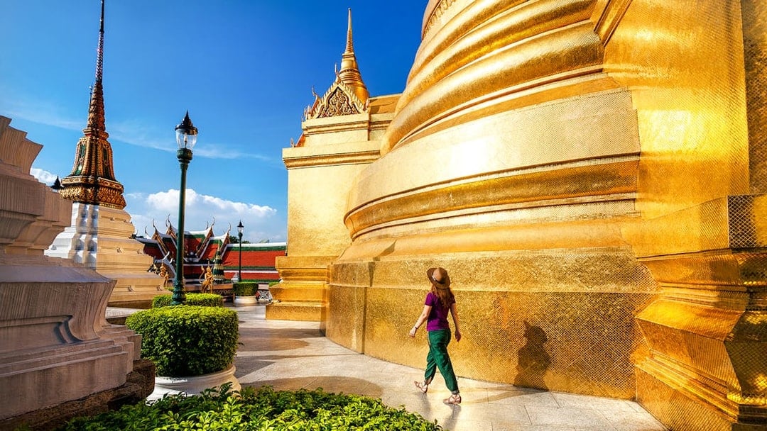 Woman walking near golden stupa at Wat Phra Kaew, Bangkok.