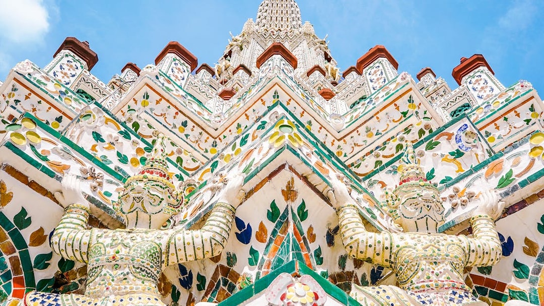 Wat Arun temple intricate facade with colorful guardian statues, Bangkok.