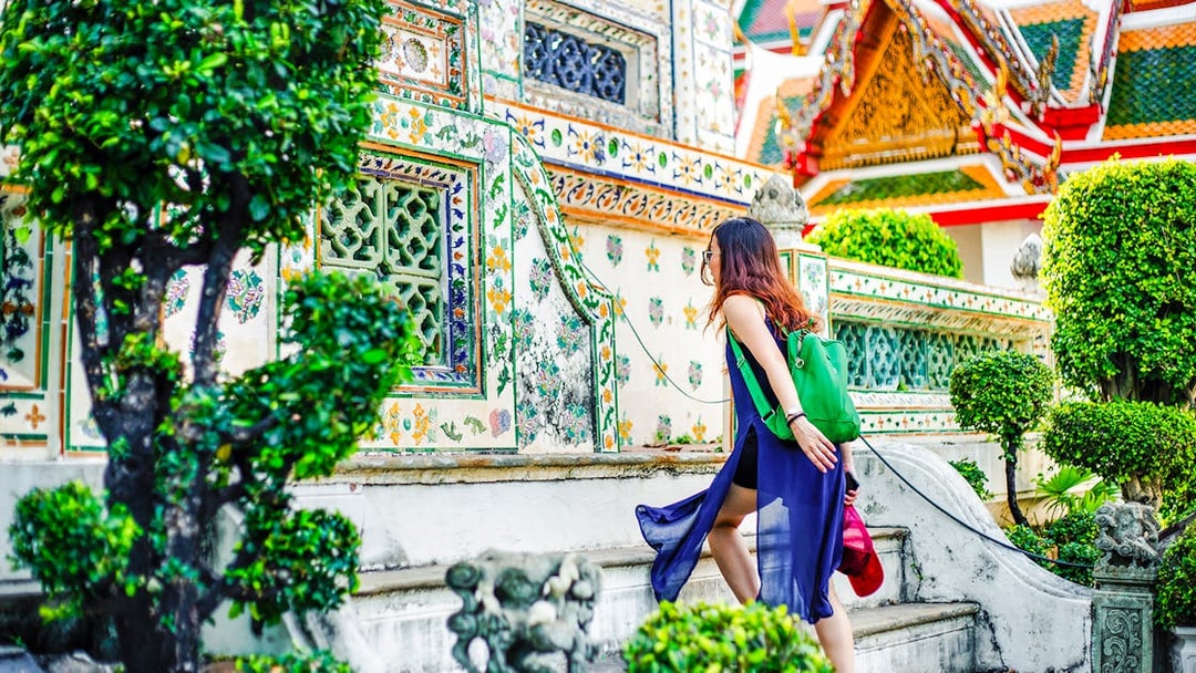 Woman climbing steps at Wat Arun temple, Bangkok.