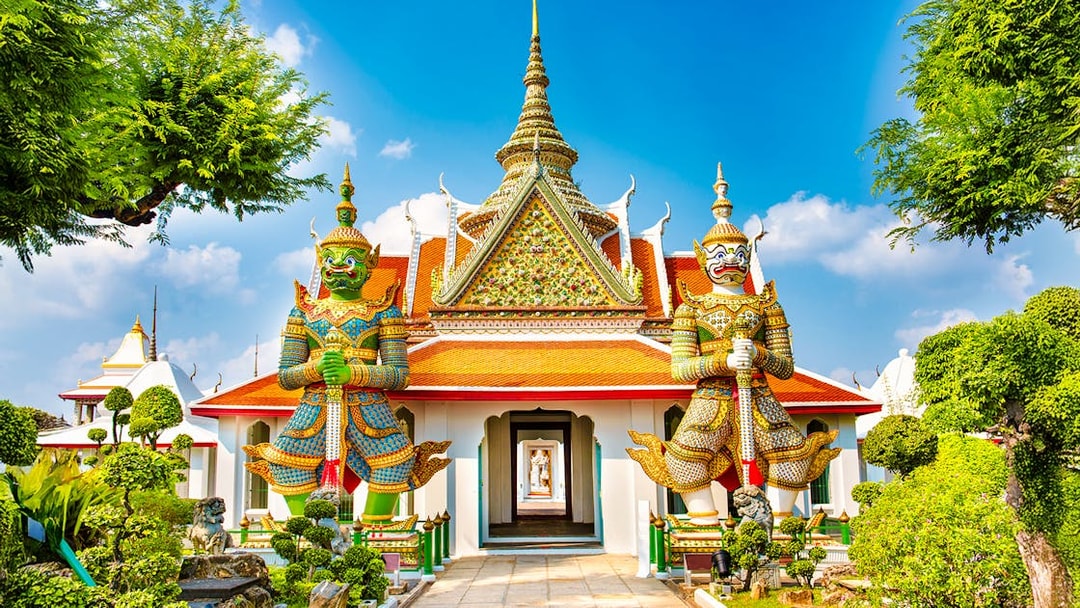 Wat Arun entrance with guardian statues, Bangkok.