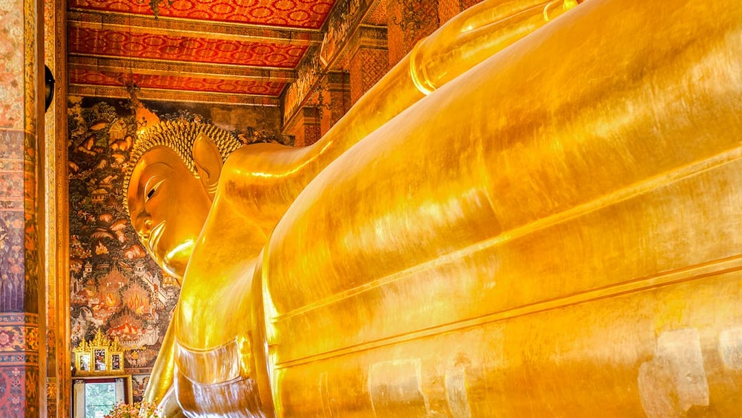 Reclining Buddha statue at Wat Pho, Bangkok, with intricate temple murals.