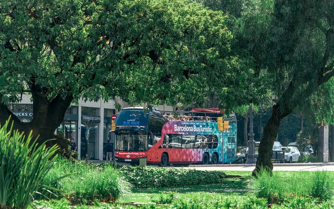 Barcelona Bus Turistic on a city street surrounded by trees.