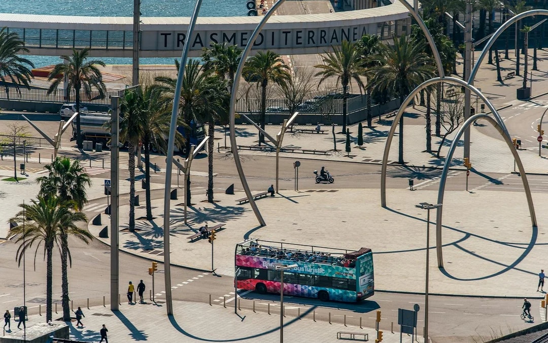 Barcelona hop-on hop-off bus near waterfront and modern sculpture.