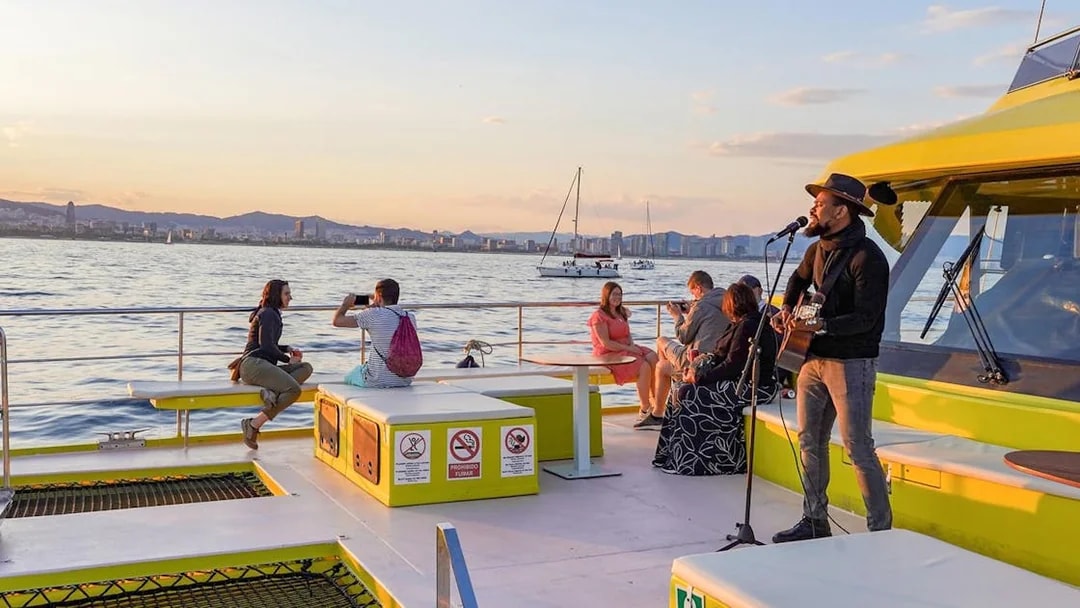 Musician performing on a Barcelona catamaran cruise at sunset.