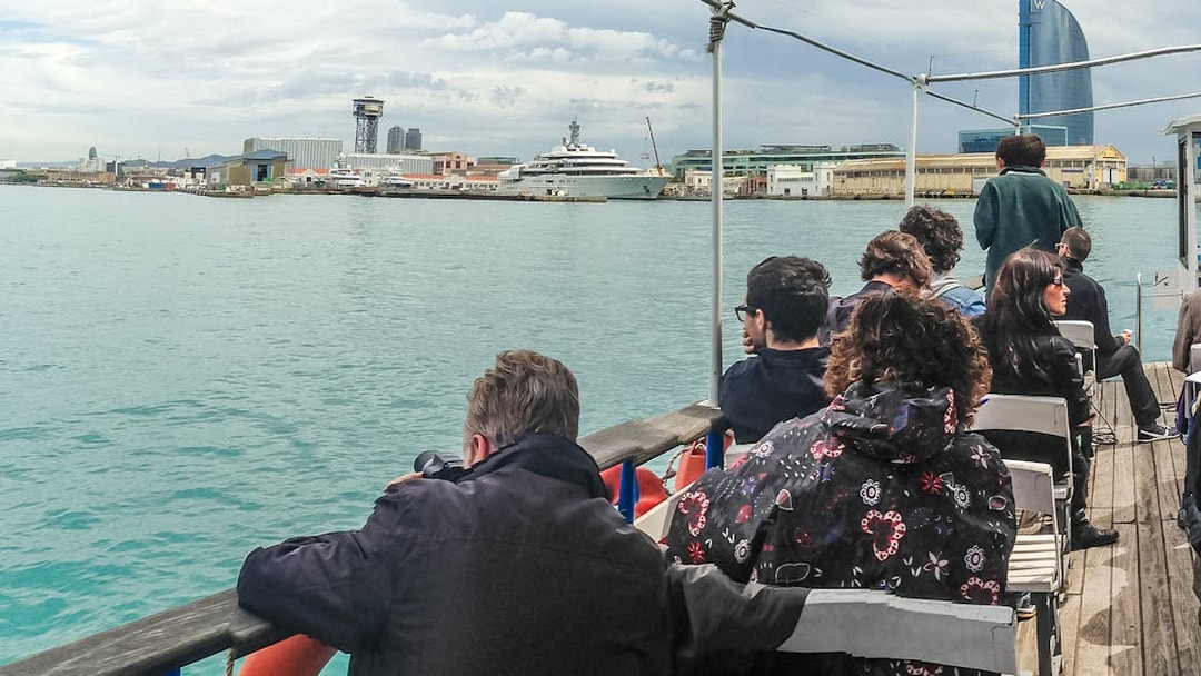 Tourists on Las Golondrinas boat viewing Barcelona skyline with W Hotel in background.