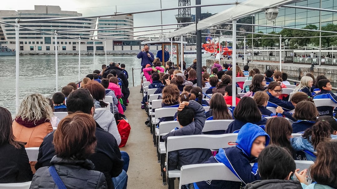 Passengers seated on Las Golondrinas boat trip in Barcelona, viewing cityscape and waterfront.