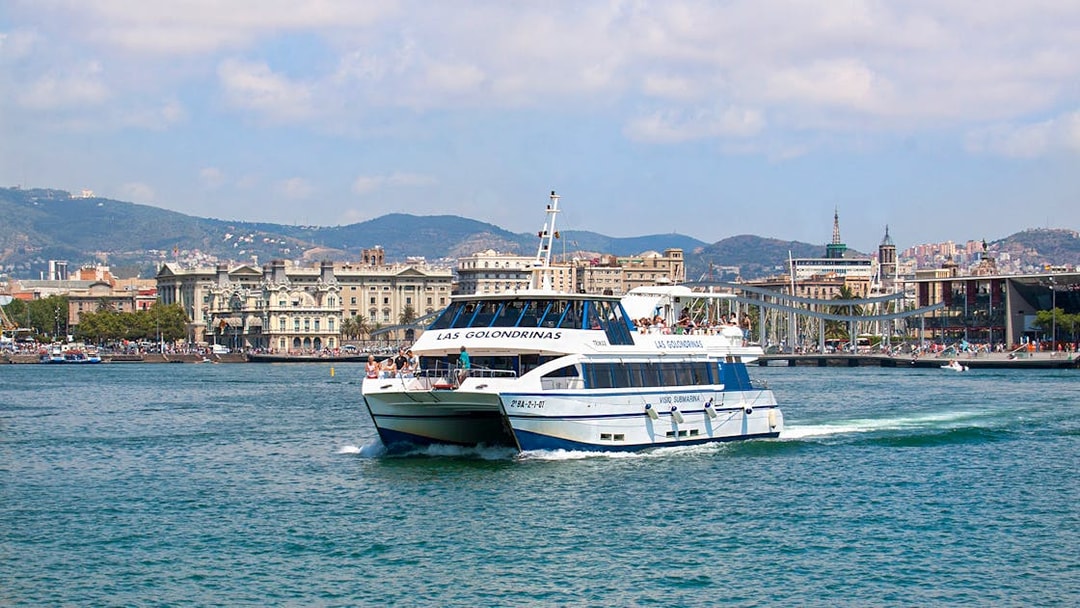 Las Golondrinas boat cruising Barcelona's coastline with city skyline.