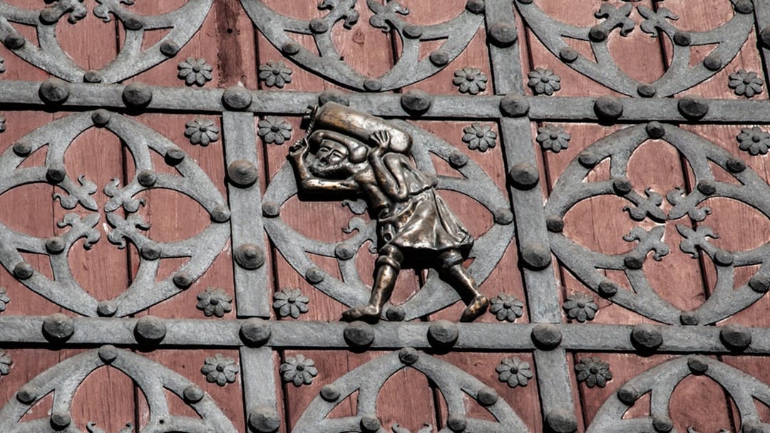Ornate metalwork on a door in Barcelona's Gothic Quarter, featuring a figure carrying a sack.
