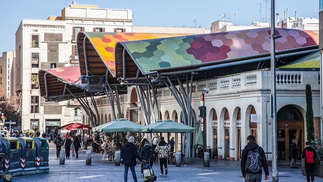 Colorful roof of Mercat de Santa Caterina in Barcelona with people walking nearby.