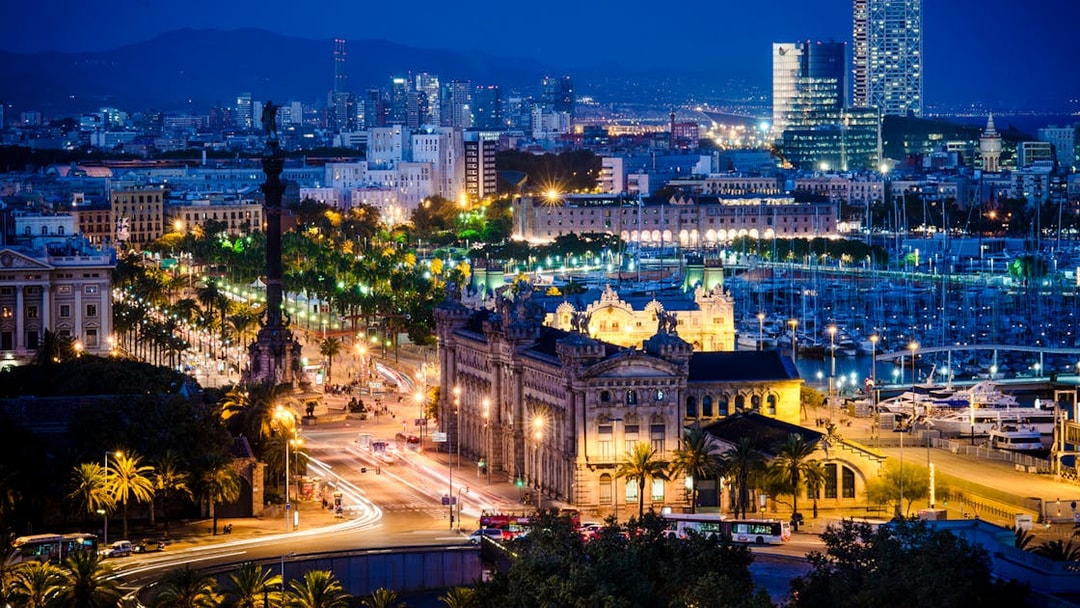 Barcelona cityscape at night with Columbus Monument and Port Vell marina.
