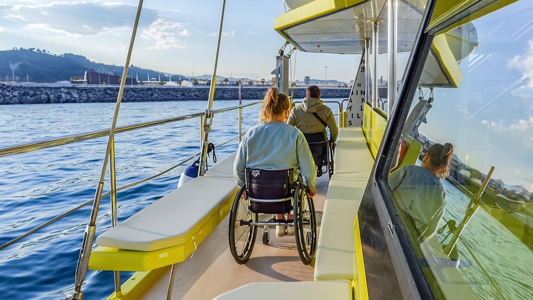 Eco catamaran cruise with passengers in wheelchairs enjoying coastal views.