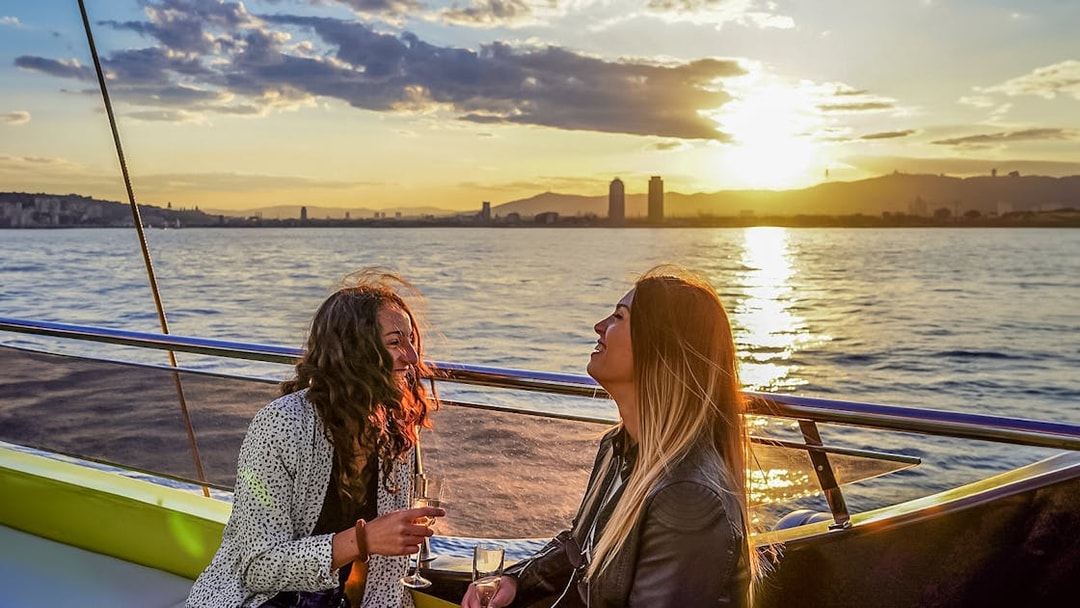 Tourists enjoying sunset aboard a catamaran cruise in Barcelona.