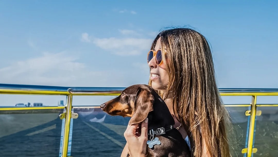 Tourist with her dog on a catamaran cruise, enjoying ocean views.