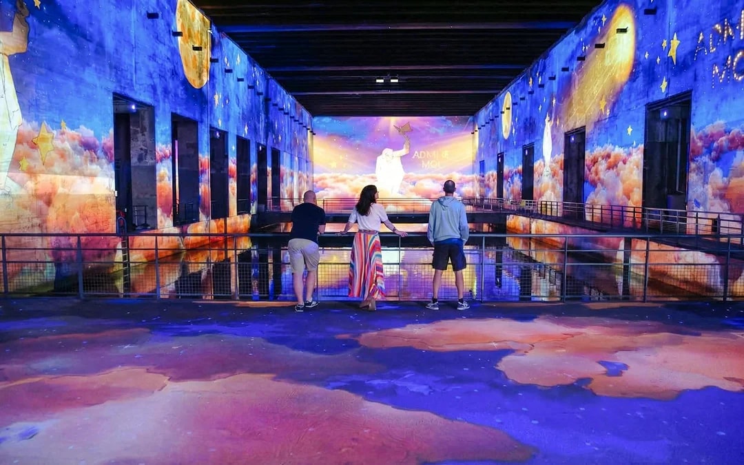 Visitors viewing "The Little Prince" immersive display at Bassins des Lumières, Bordeaux.