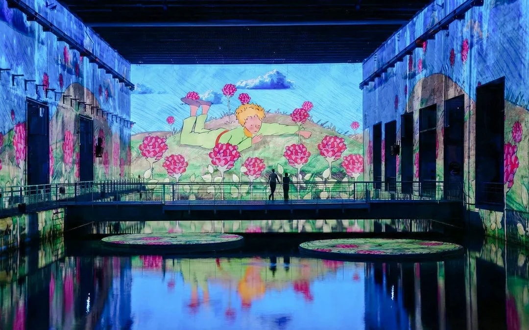 The Little Prince projection at Bassins des Lumières, Bordeaux, with vibrant floral visuals.