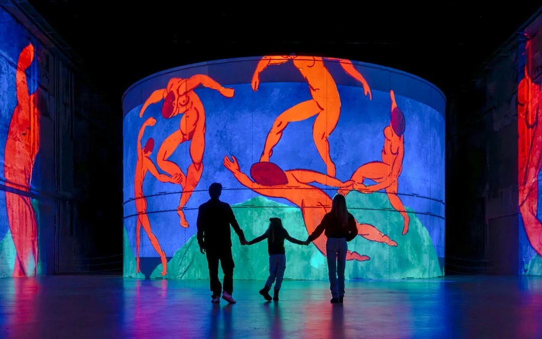 Family viewing Matisse's "Symphony of Colors" at Bassins des Lumières exhibition.