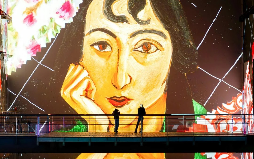 Matisse artwork projection at Bassins Des Lumieres exhibition with visitors on a bridge.