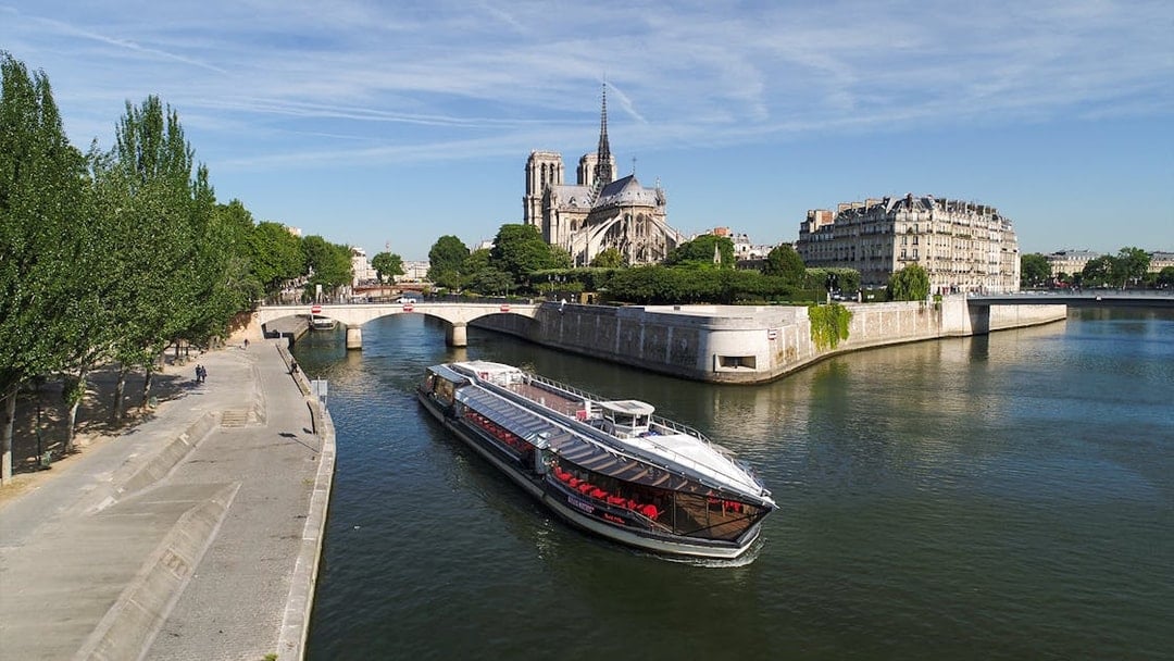 Seine River cruise boat near Notre-Dame Cathedral in Paris.