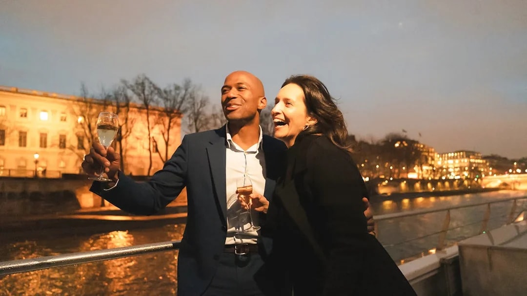 Couple enjoying a boat ride on Bateaux Mouches in Paris at night.