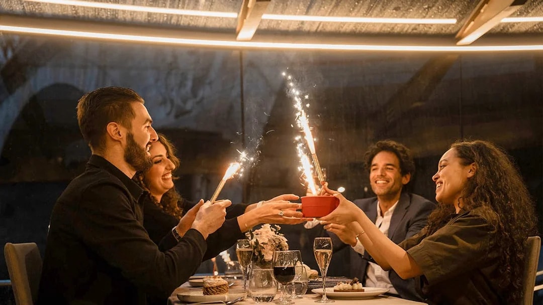 Guests enjoying a festive dinner with sparklers on a Seine River cruise in Paris.