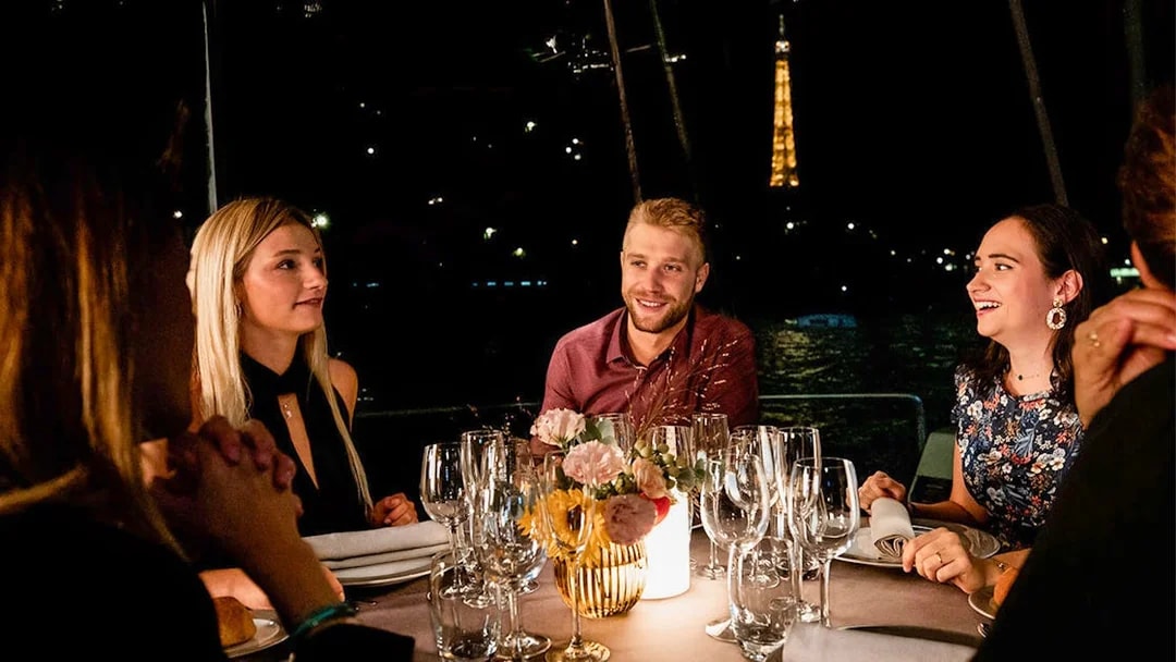 Guests dining on a Seine River cruise with Eiffel Tower view.