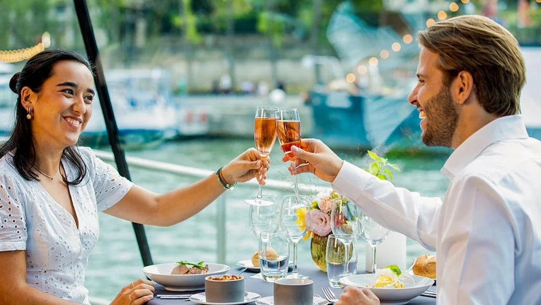 Couple toasting with champagne on a Seine River dinner cruise in Paris.