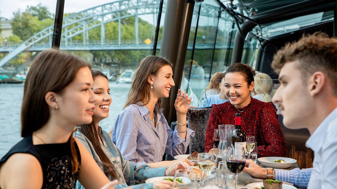 People dining on a Seine River lunch cruise with a view of a bridge in Paris.