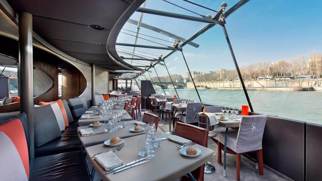 Seine River lunch cruise dining area with set tables and river view.