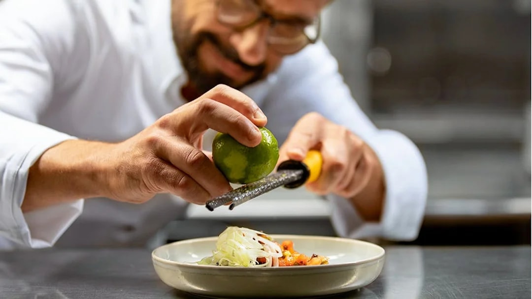 Chef zesting lime over dish on Seine River lunch cruise, Paris.