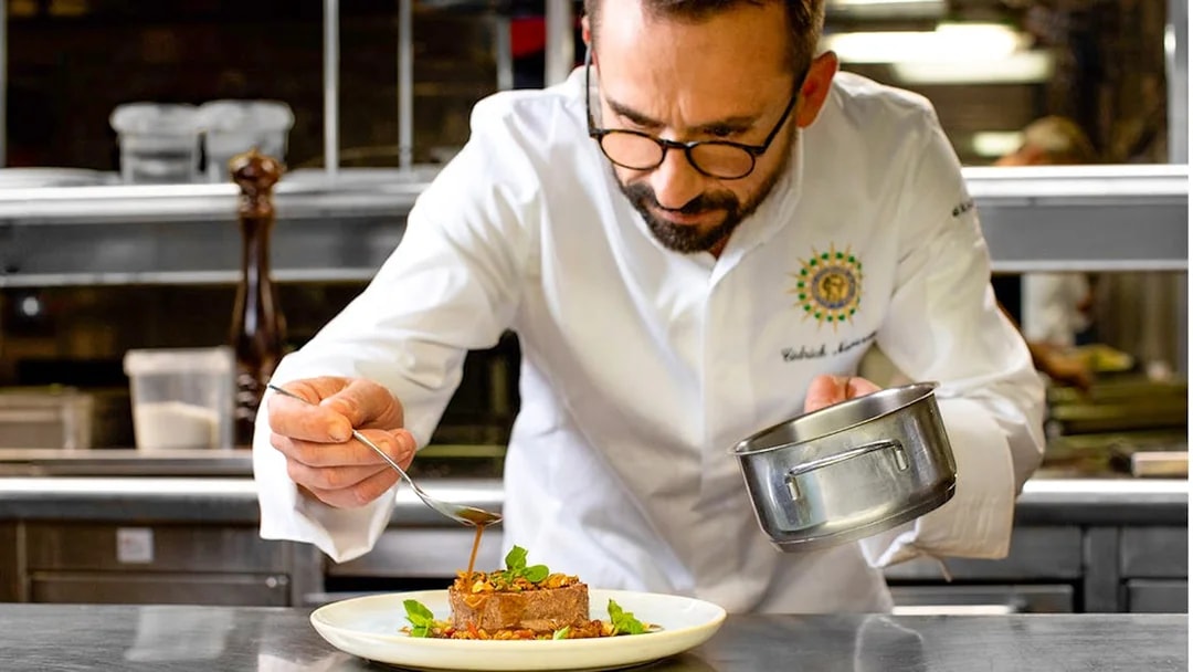 Chef preparing gourmet dish for Seine River lunch cruise on Bateaux Parisiens.