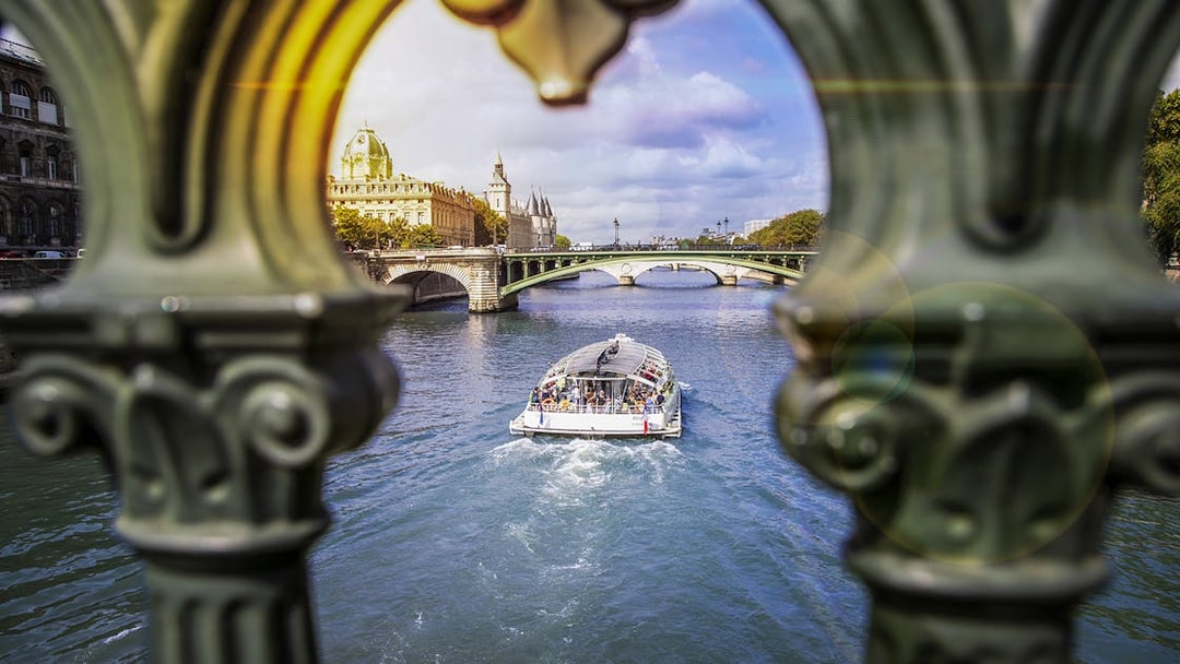 Batobus cruising on the Seine River in Paris with historic buildings and bridge in view.