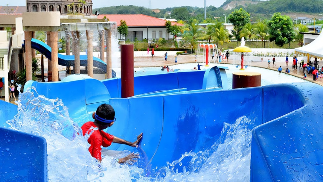 Child sliding down a blue water slide at Bayou Lagoon Water Park.
