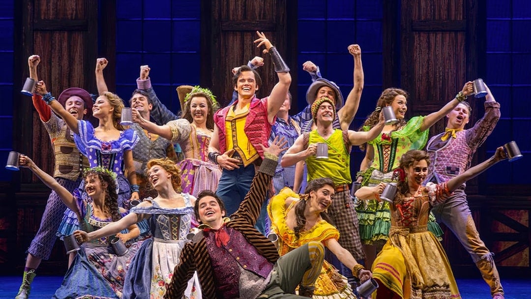 Cast performing a lively tavern scene from Beauty and the Beast musical.
