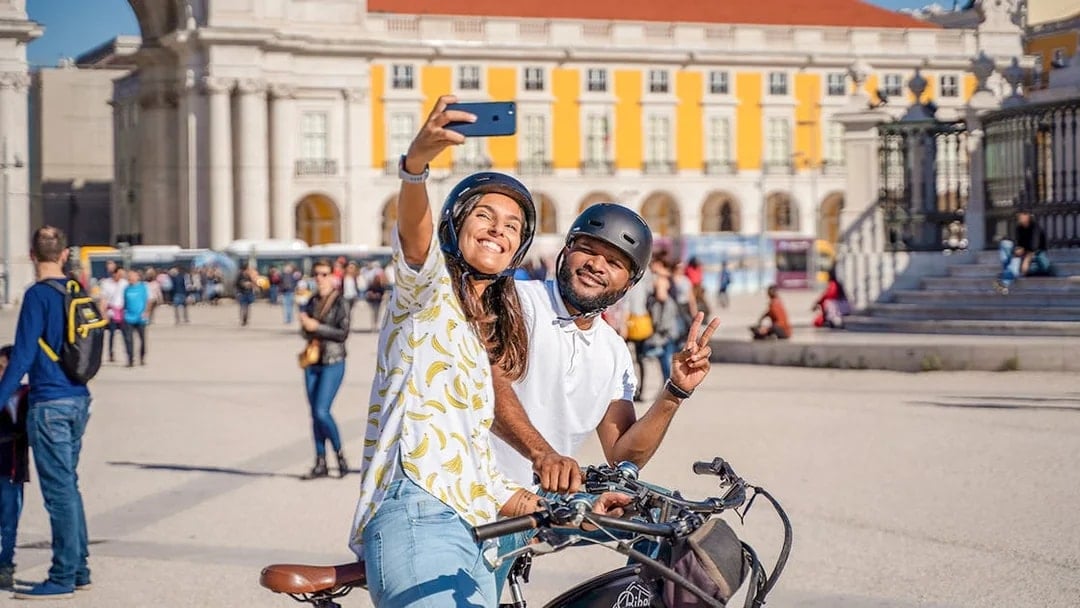 Couple taking a selfie on bikes at Commerce Square, Lisbon.