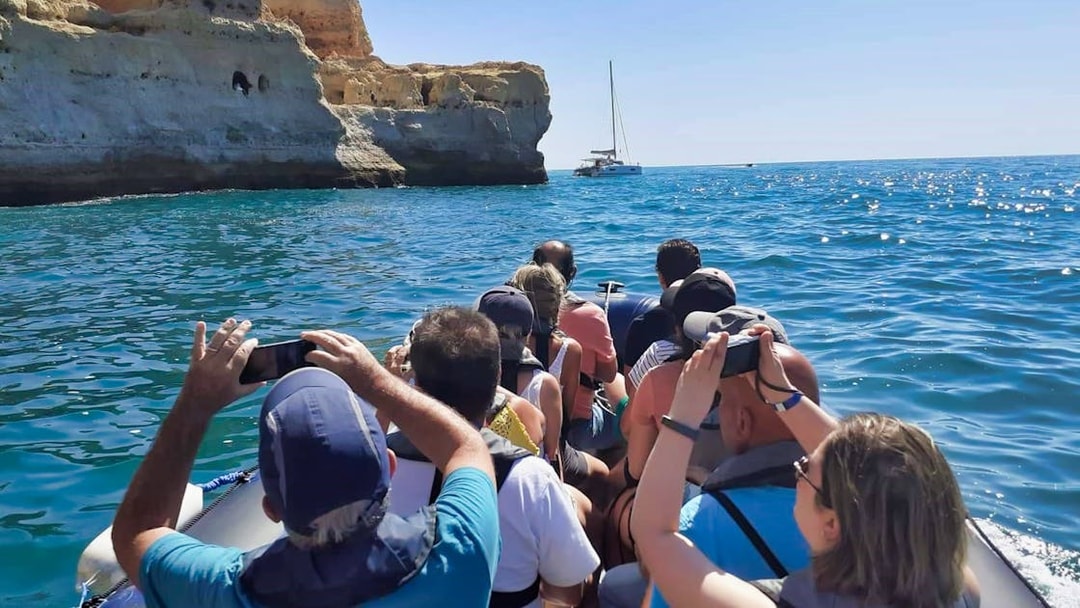 Tourists on a boat approaching cliffs near Benagil Cave, Algarve coast.