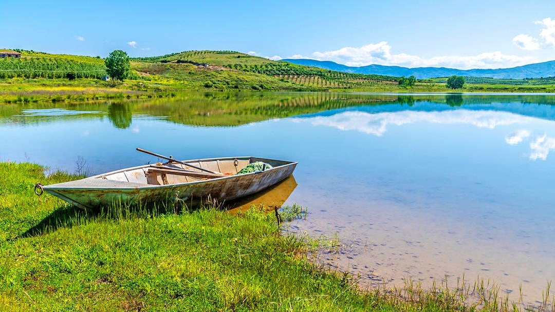 Boat on the shore of Belshi Lake with hills in the background.